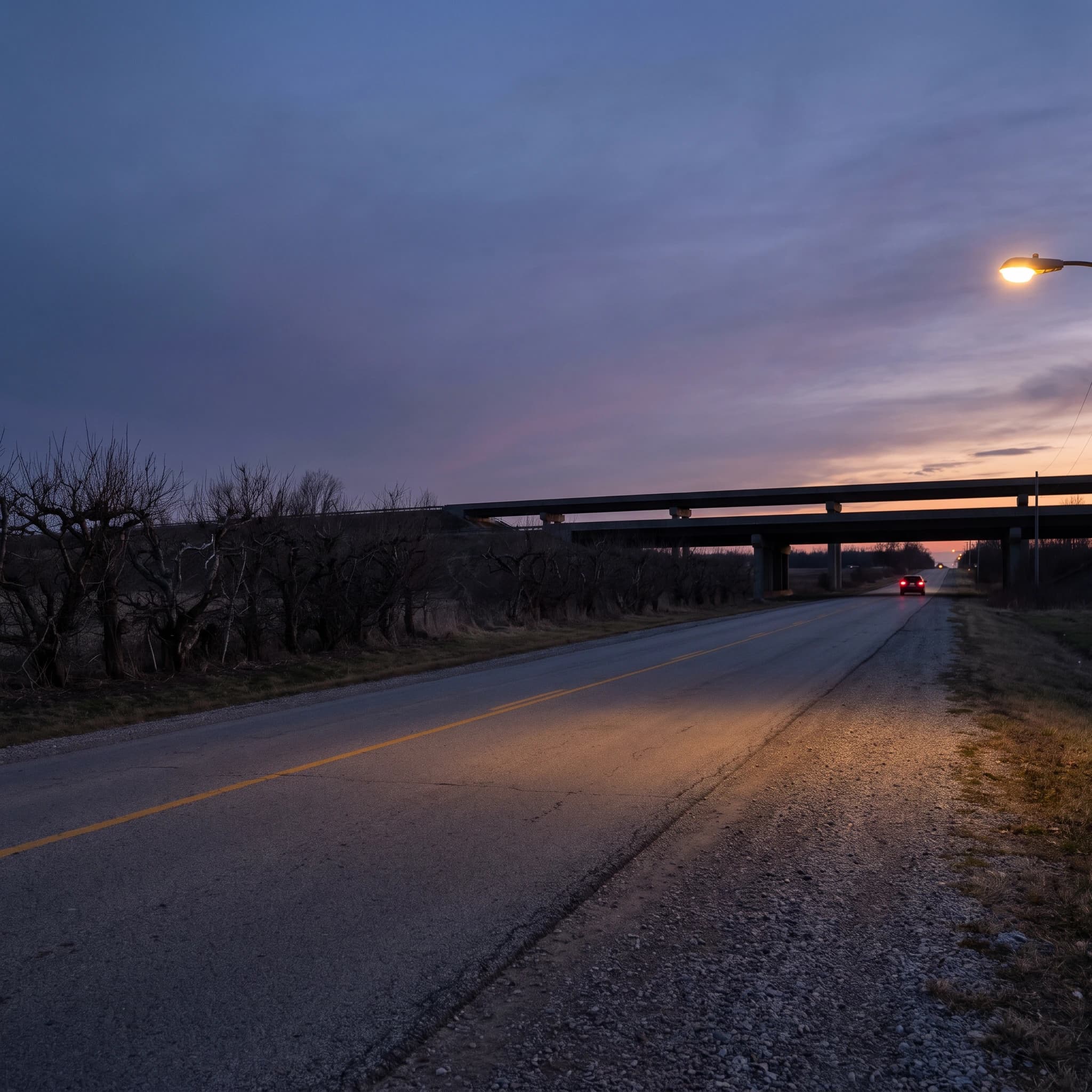 Quiet rural road at dusk leading toward a highway overpass south of Guelph